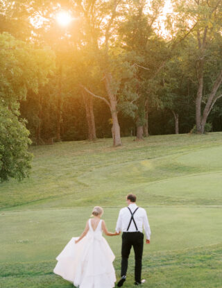 bride and groom holding hands and walking onto golf course at Cooper Creek