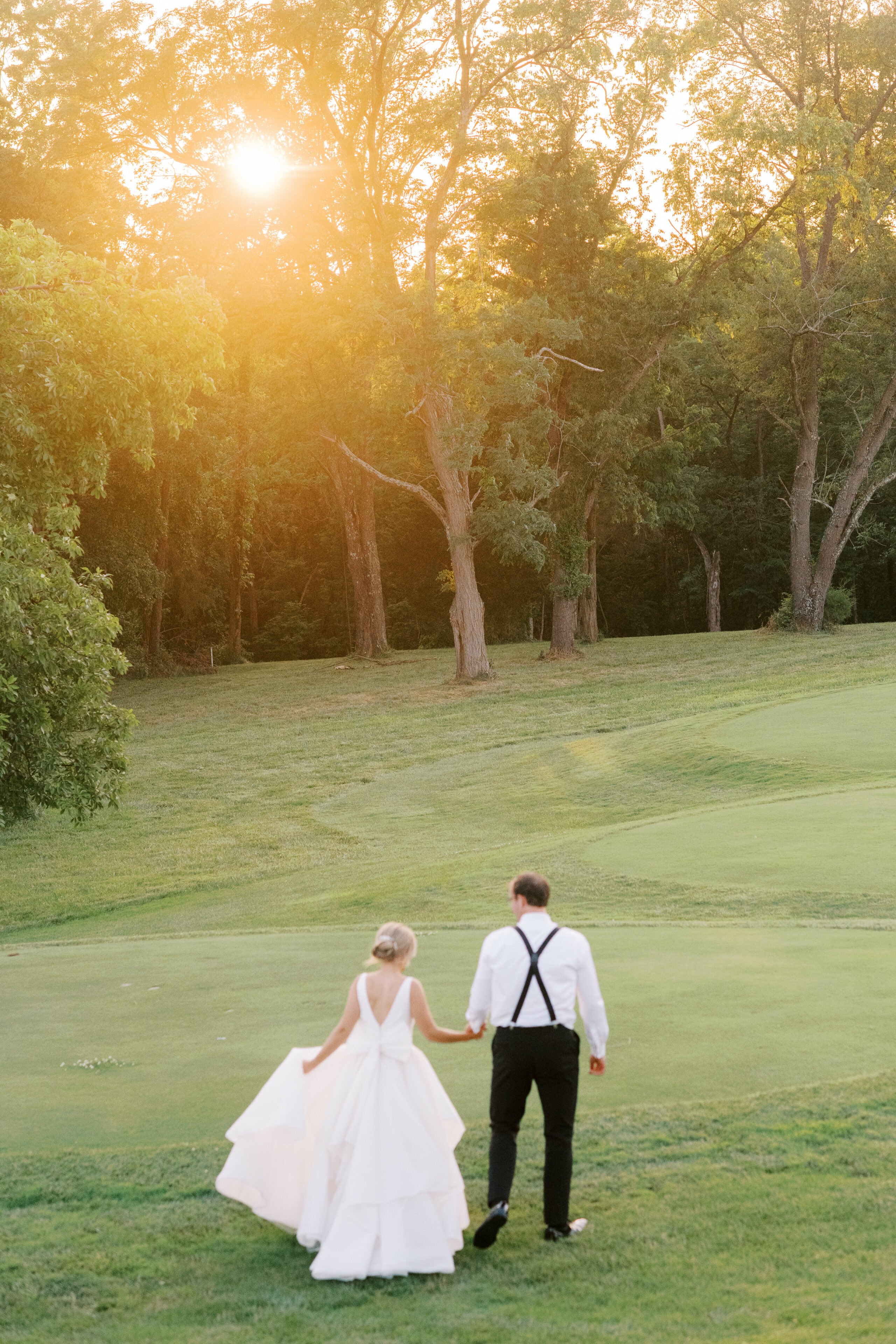 bride and groom holding hands and walking onto golf course at Cooper Creek