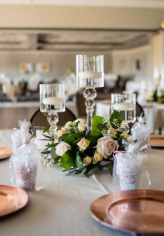 Table decorated with cooper plates, glass cups with candles, and flowers