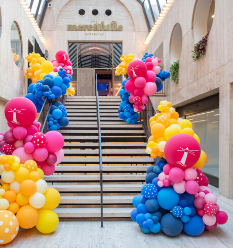 A staircase decorated with colorful balloon clusters in a modern indoor space.