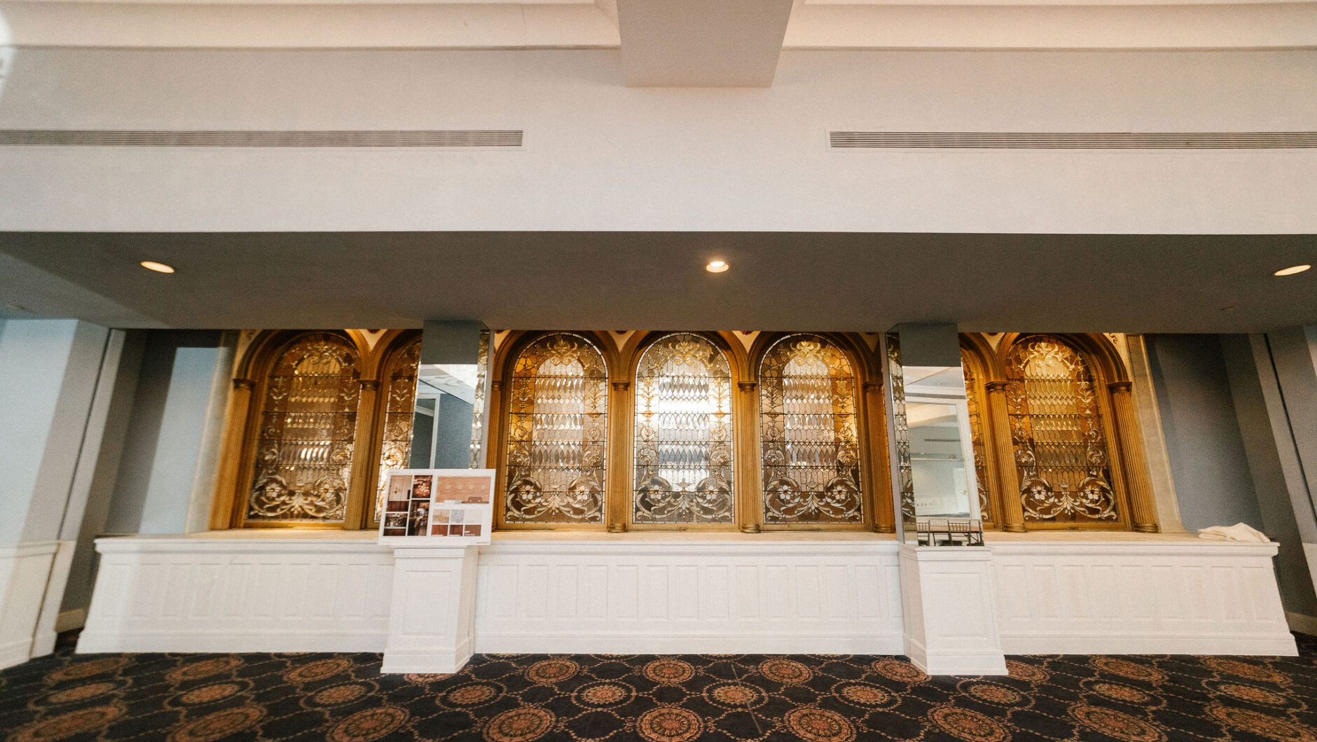 Elegant counter with ornate gold arches, mirrors, and patterned carpet in a spacious, well-lit room.