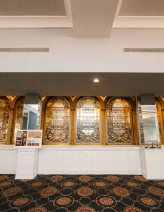 Elegant counter with ornate gold arches, mirrors, and patterned carpet in a spacious, well-lit room.